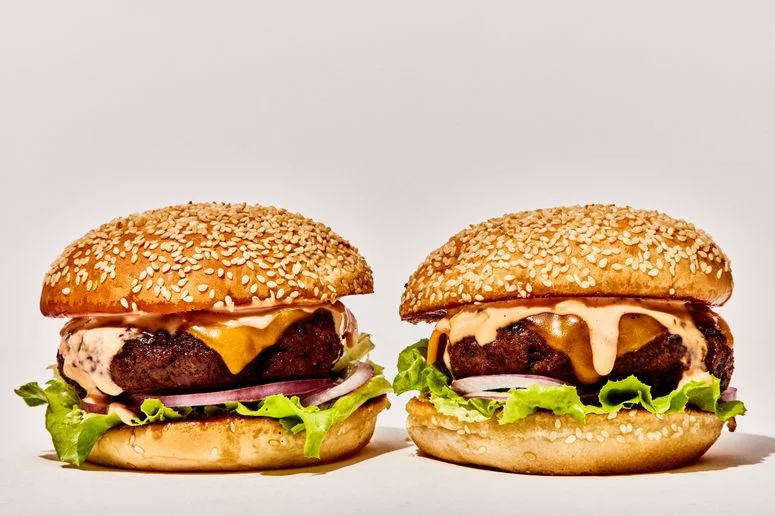 Two cheeseburgers on seeded buns with lettuce red onion and secret sauce.