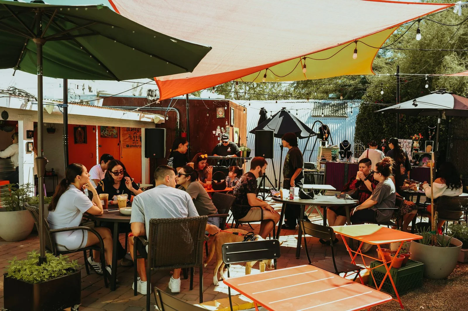 A populated outdoor dining patio with various colored canopies.