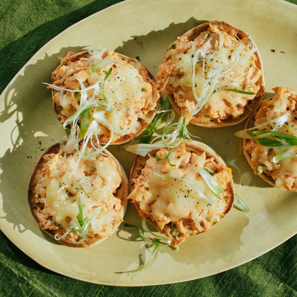 Five toasted English muffins topped with kimchi tuna melted cheese and sliced scallions.