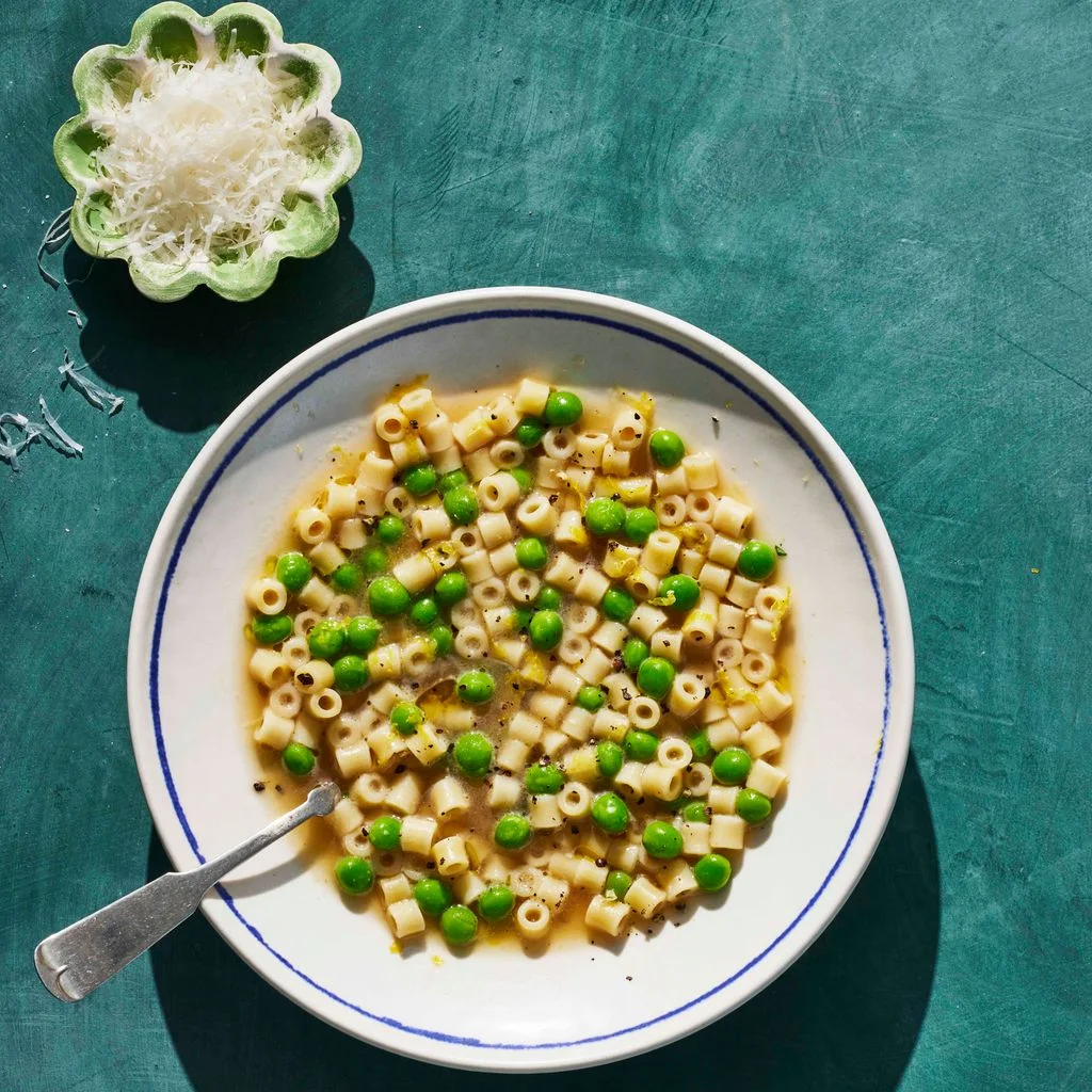 Ditalini and Peas in Parmesan Broth in a bowl with cheese on the side