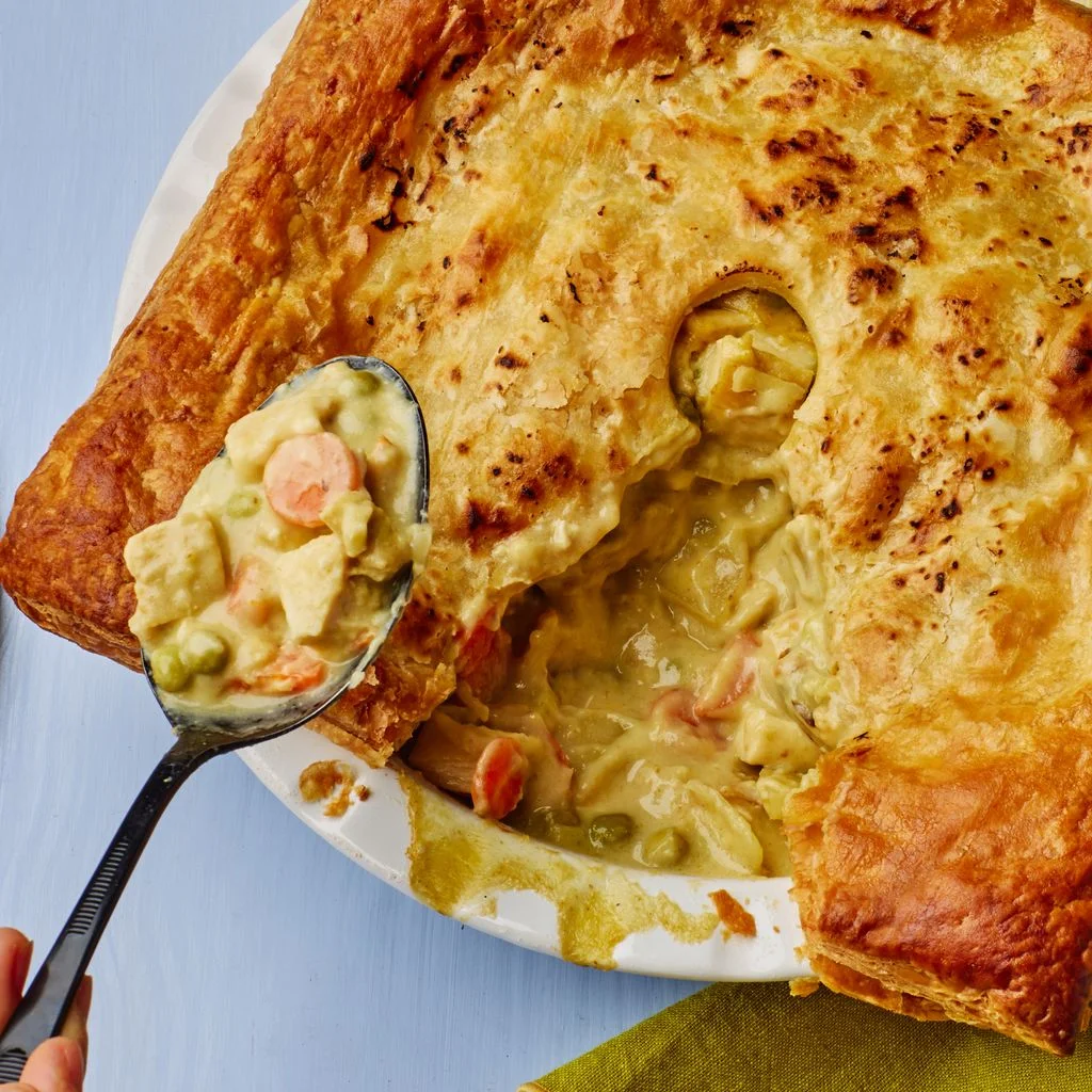 Thai Curry Chicken Pot Pie in a rounded white bowl on a blue surface