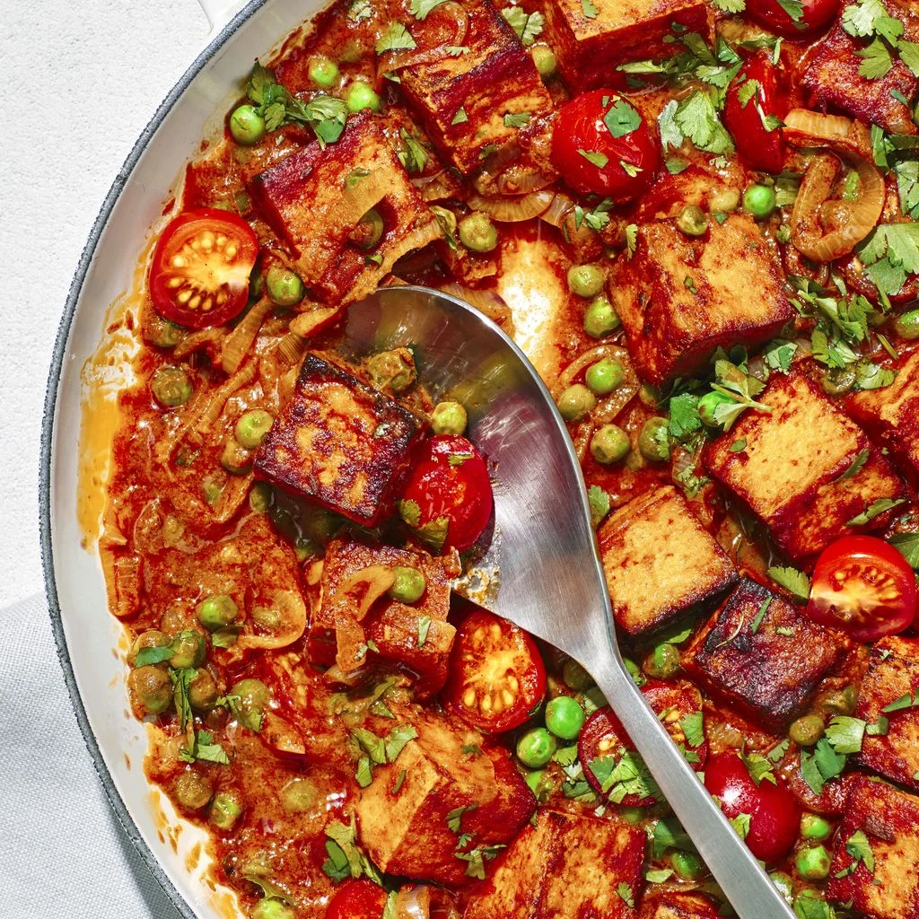 Tofu and Green Pea Curry in a pan with a serving spoon removing a portion