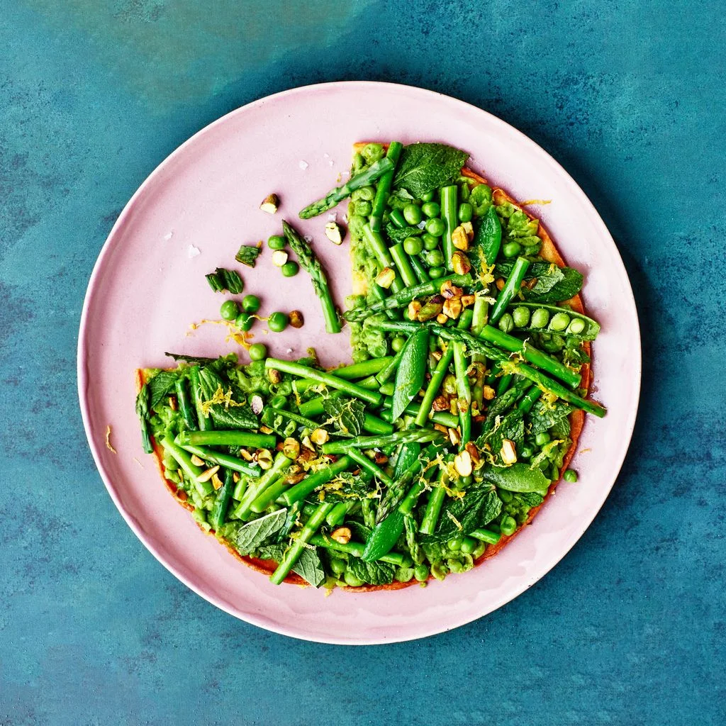 A chickpea pancake on a pink dish over a blue background