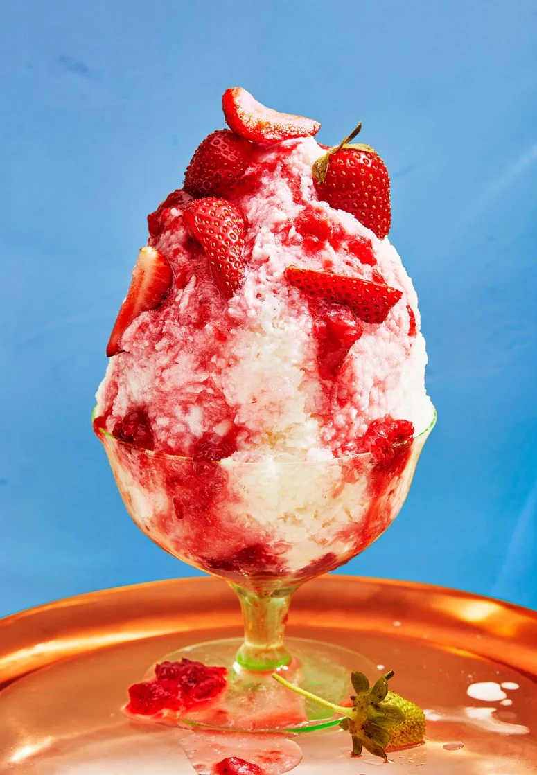 a cup of shaved milk with strawberries on a blue background