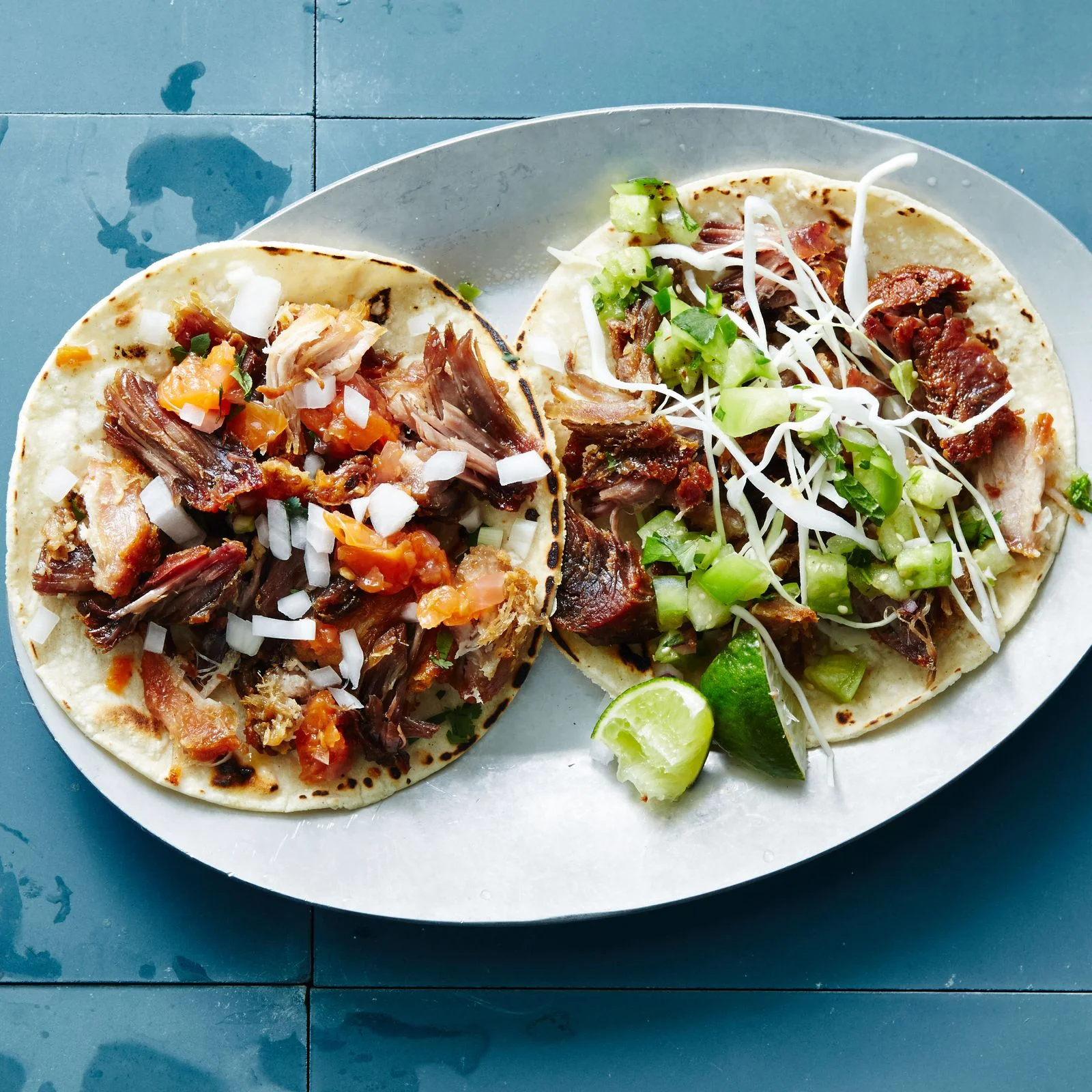 Two carnitas tacos on a plate.